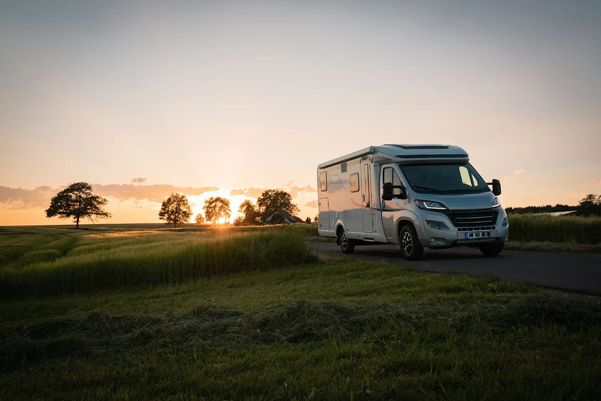 Camper semintegrale al tramonto su strada in mezzo al parco